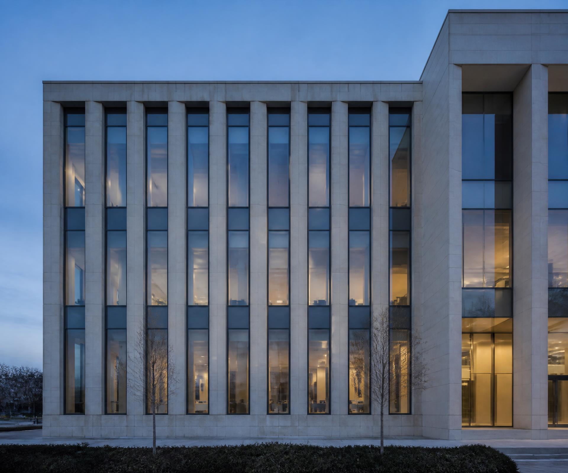 Institutional limestone facade with a disciplined structural rhythm at dusk
